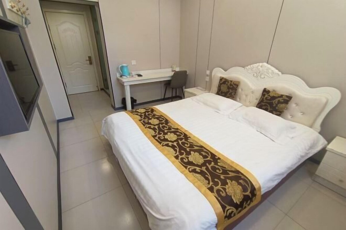 A hotel room with a bed, a desk, and a chair.