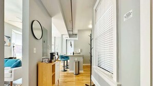 A modern living room with a wooden cabinet, a round mirror, and a blue chair. - Boho Studio Loft in OTR Near Downtown Cincy (Cincinnati)