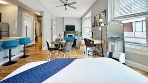 A modern hotel room with a large bed, a desk, and a dining area. - Boho Studio Loft in OTR Near Downtown Cincy (Cincinnati)