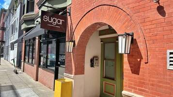 Un edificio de ladrillo con un escaparate que dice "sugar" y una puerta verde.