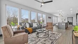 Ein geräumiges Wohnzimmer mit Sofa, Sessel, Couchtisch und Deckenventilator.