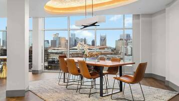 Un espace de restauration moderne, doté d’une grande table, de chaises et offrant une vue sur la ville grâce à de larges fenêtres.