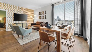 A modern living room with a sofa, armchair, and dining table. - 2 King Suites Walk to Broadway & Gulch (Nashville)