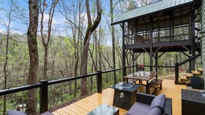 A wooden deck with outdoor furniture, a barbecue grill, and a covered area with a staircase. - Cozy, creekside cottage in beautiful Dawsonville (Dawsonville)