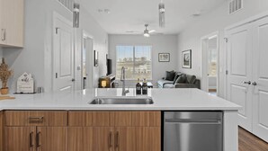 Una cocina moderna con una isla central, armarios blancos y un lavavajillas.