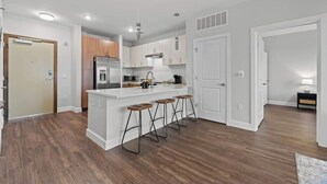 Una cocina moderna con una isla central, taburetes de bar y un microondas.