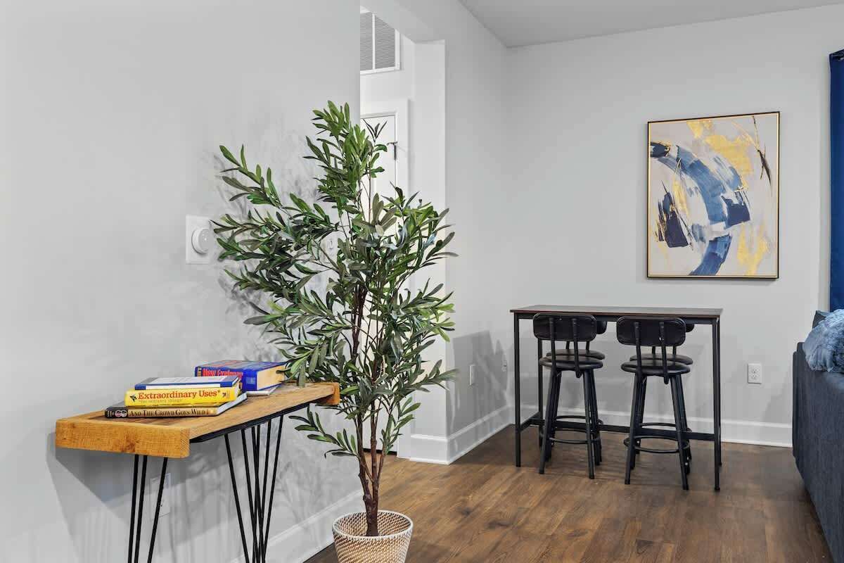A modern living room with a wooden table, a potted plant, and a painting on the wall.