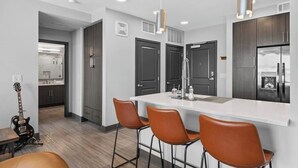 Een moderne keuken met een centraal eiland, donkere kastjes en een gitaar in de hoek.