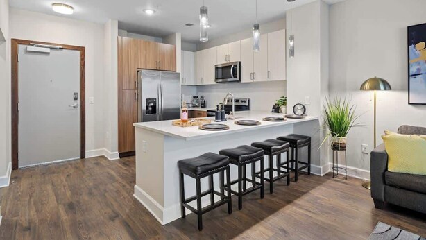 A modern kitchen with a central island, bar stools, and a dining area. - Luxe Gulch 1BR near Broadway | Sleeps 6 (Nashville)