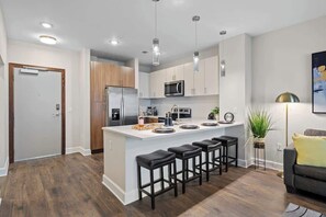 A modern kitchen with a central island, bar stools, and a dining area. - Luxe Gulch 1BR near Broadway | Sleeps 6 (Nashville)