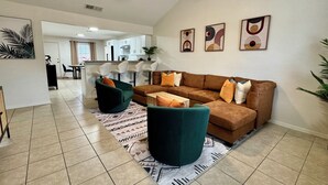 A spacious living area with a brown sofa, green armchairs, and a patterned rug. A ceiling fan and recessed lighting are visible. - Swim, Hike, Explore & Relax just minutes from lakes-beaches, nature & Ft. Worth! (Azle)
