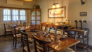 Zona pranzo con tavoli e sedie in legno, angolo buffet e postazione per caffè.