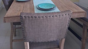 Une table à manger avec des assiettes turquoise et un chandelier blanc, le tout placé devant un mur jaune orné de panneaux décoratifs.