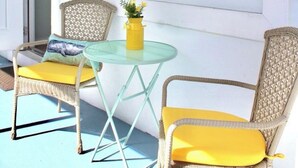 A room with two wicker chairs, a small glass table, and a yellow vase with flowers. - Salt + Sun Studio, feet from Hollywood Beach (Hollywood)