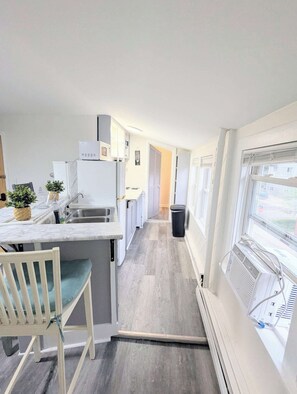A narrow kitchen with a built-in stove, a sink, and a window.