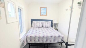 A bedroom with a bed, a window, a painting, and a ceiling light. - 1 BD 7 minutes to 7 mile beach. Sleeps 3 and pet freindly<br>- FREE parking<br>- queen bed and futon<br>- fast wifi<br>-smart TV<br>- BBQ, Picnic table and fire pit (Old orchard beach)