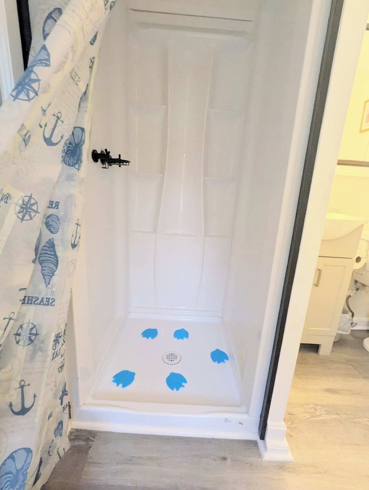 Un espacio de ducha pequeño y cerrado, con interior blanco y una puerta con pomo negro.