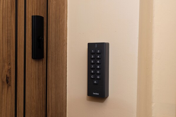 A door with a modern keypad lock and a wooden panel. - Gold - by Kairos Apartments (Gliwice)