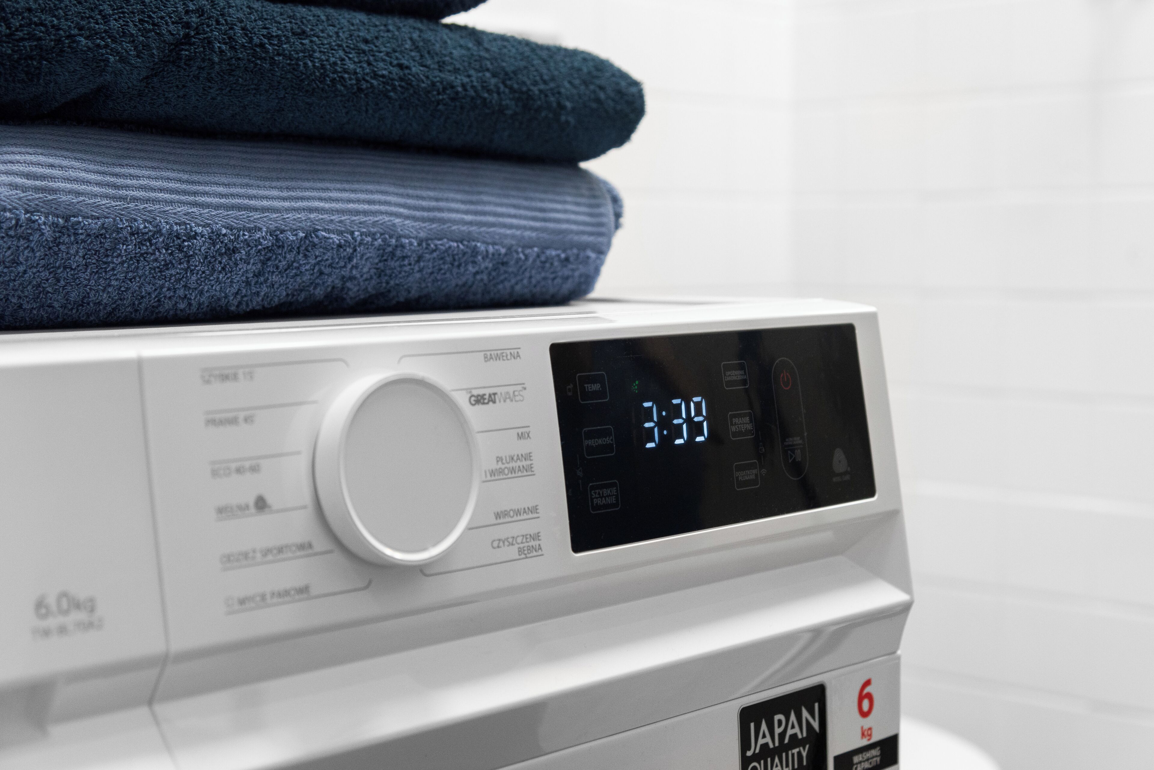 A front view of a washing machine with a digital display, a dial, and a label indicating a 6 kg capacity.