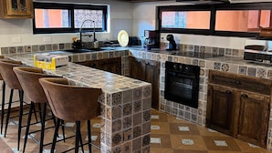 A modern kitchen with a central island, bar stools, a built-in oven, and a backsplash with patterned tiles. - Casa Colonial en Pueblo Mágico by Adhoc (Santiago)