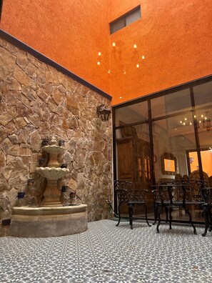 A stone wall with a tiered fountain, outdoor seating, and a glass door leading inside. - Casa Colonial en Pueblo Mágico by Adhoc (Santiago)