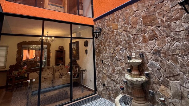 Un patio amplio con muro de piedra, una fuente y un área de estar.