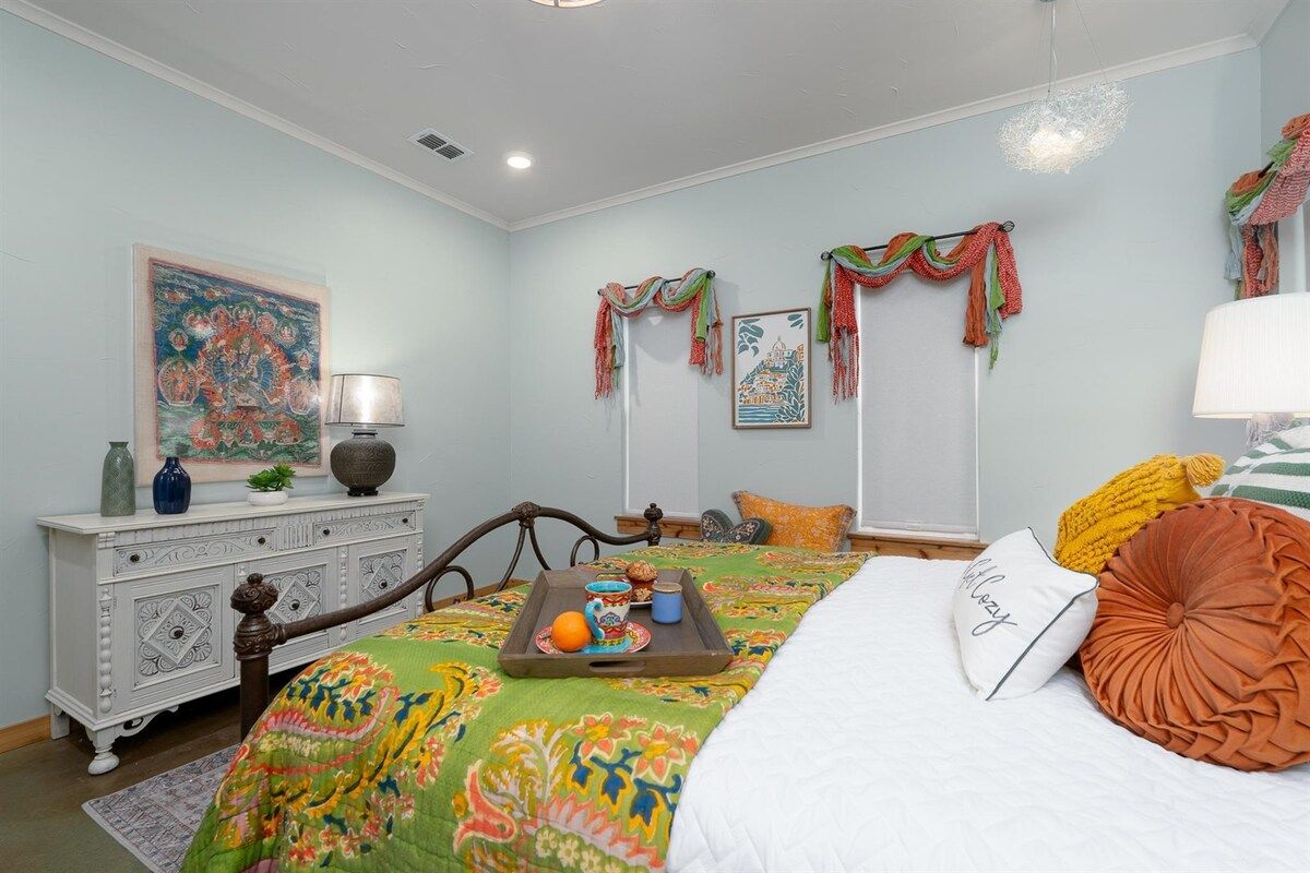 A bedroom with a bed, a dresser, a painting, and a tray with items on it.