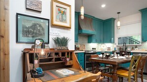 A dining area with a wooden table, chairs, a clock, and a framed picture on the wall.