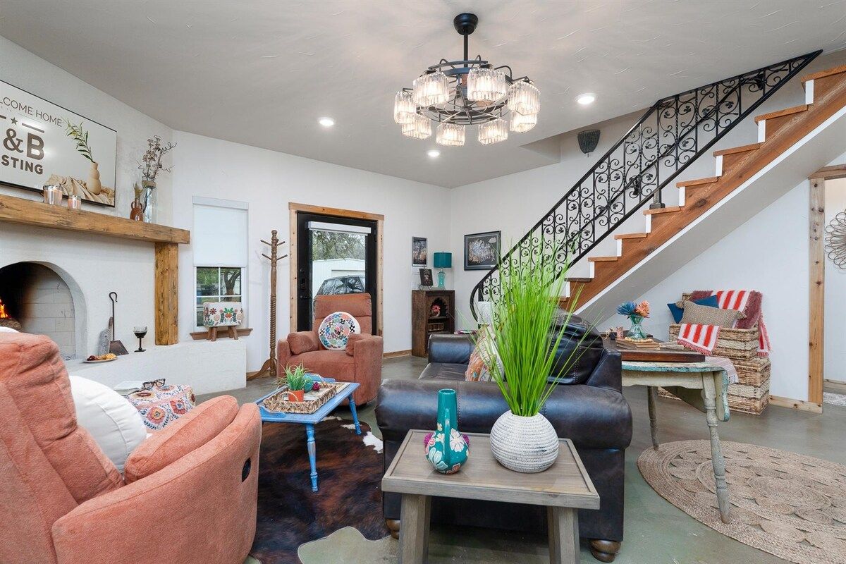 A living room with a fireplace, a staircase, and a chandelier.
