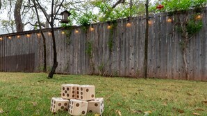 A grassy area with a wooden fence and string lights.