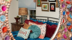 A bedroom with a bed, pillows, a lamp, and framed artwork on the wall.