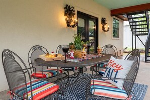 A covered patio area with a round table and chairs, a decorative wall, and a view of the backyard.