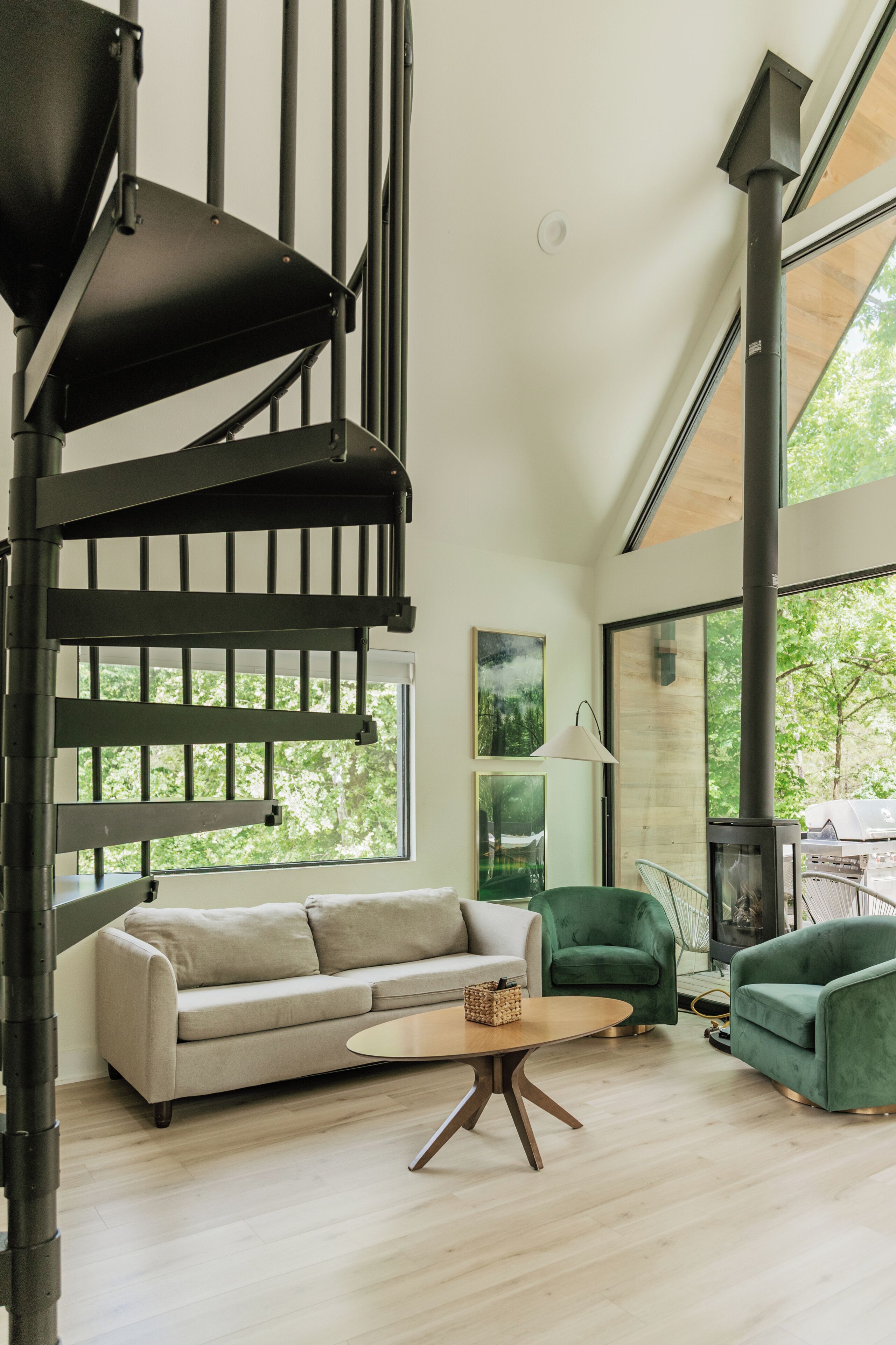Un interior moderno con una escalera de caracol, un sofá, un sillón verde y una mesa.