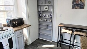 A kitchen with a stove, microwave, and a white cabinet with shelves. - Updated studio 7 minute walk to beach.  FREE Park! (Old Orchard Beach)