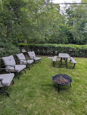 Un espacio al aire libre con césped, una chimenea, una mesa y varias sillas.