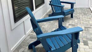 Dos sillas Adirondack frente a un edificio con ventanas amplias y fachada blanca.