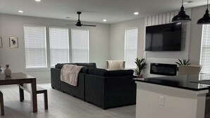 Una sala de estar moderna con sofá, televisión y una zona de cocina.