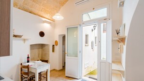 Una cocina con una mesa de comedor, sillas, una botella de vino y una puerta que da al exterior.