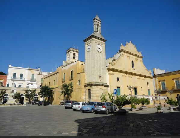 A historic building with a clock tower, parked cars, and a clear blue sky.