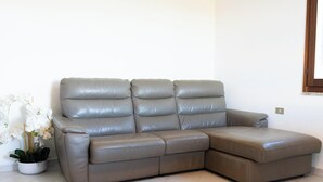 A sectional sofa in a corner of a room with a white wall and a window. - Apartment 'Malamuri 1' with Shared Pool, Shared Garden and Wi-Fi (Budoni)