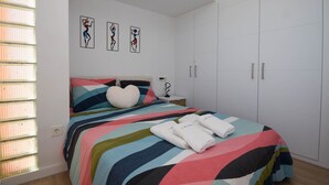 A bedroom with a bed, colorful striped bedding, a white wardrobe, and artwork on the wall. - Ref: 262 Beach front apartment with amazing terrace and sea views (Fuengirola)