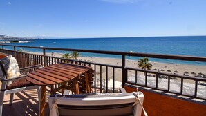 A balcony with wooden furniture overlooking a beach. - Ref: 262 Beach front apartment with amazing terrace and sea views (Fuengirola)