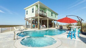 A two-story house with a swimming pool, a covered deck, and outdoor furniture. - Sunchaser (Galveston)
