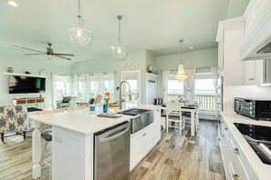 A spacious kitchen with a central island, white cabinetry, and a dining area with a view.