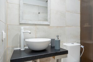 A bathroom with a white sink, a black countertop, a mirror, and a toilet.