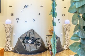 Ein Zimmer mit einer Wanduhr, zwei Sitzsäcken, einer Pflanze und einem kleinen Tisch mit einer Dekoration.