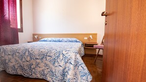 A bedroom with a bed, a wooden headboard, a nightstand, and a chair.