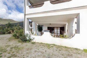 Ein modernes Gebäude mit einem überdachten Außenbereich, einem Balkon und Blick auf die umliegende Landschaft.