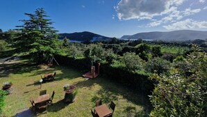 Un jardín con asientos al aire libre, una estructura de madera y vistas a montañas y un lago.
