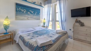 A bedroom with a bed, a TV, a dresser, a painting, and a window with curtains. - Apartment 'Casa 20' with Private Terrace, Wi-Fi and Air Conditioning (Stintino)